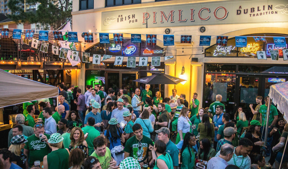 A crowd of green-clothed people outside of a pub
