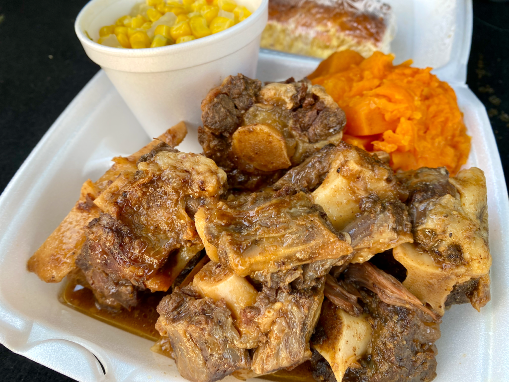 a container full of oxtail and sides from Tha neighborhood Kitchen