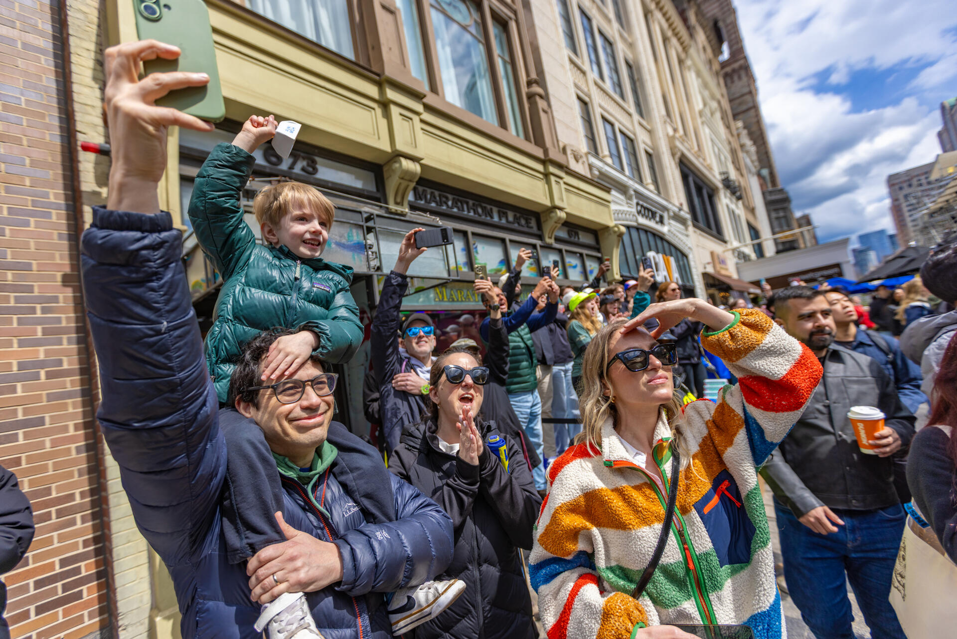 Fans in front of Marathon Sports cheer as John Korir finishes to defend his title as the Boston Marathon men’s champion. (Jesse Costa/WBUR)