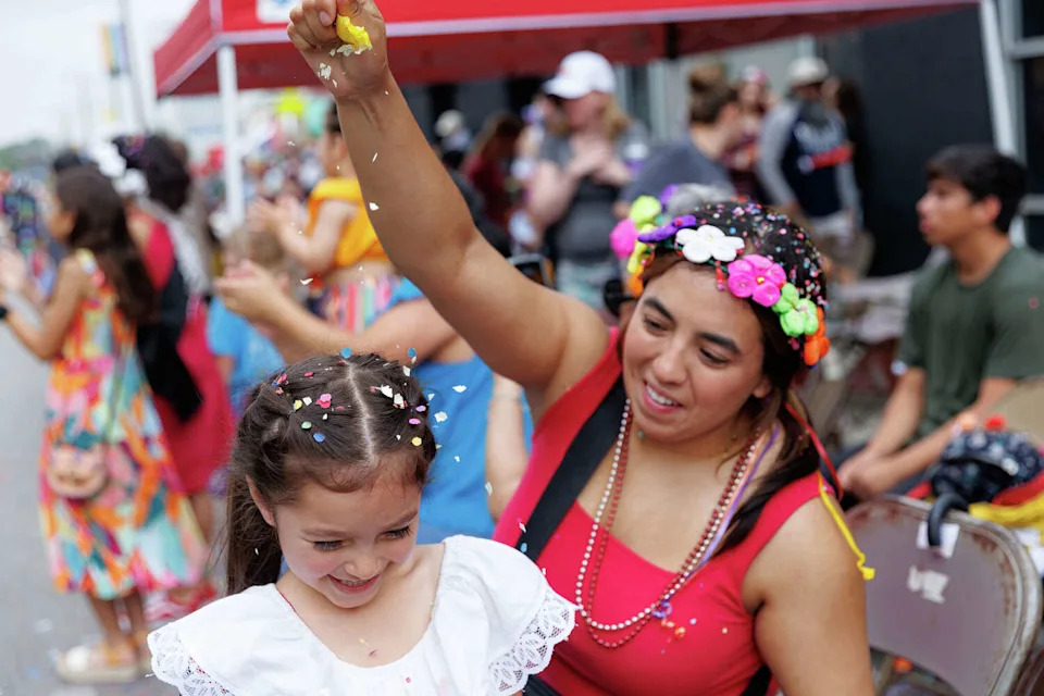 Leah Garza breaks a cascaron over Lucia Vasquez, 4, as they watch the 134th Battle of Flowers parade in San Antonio in May 2025. (Sam Owens/San Antonio Express-News file photo)