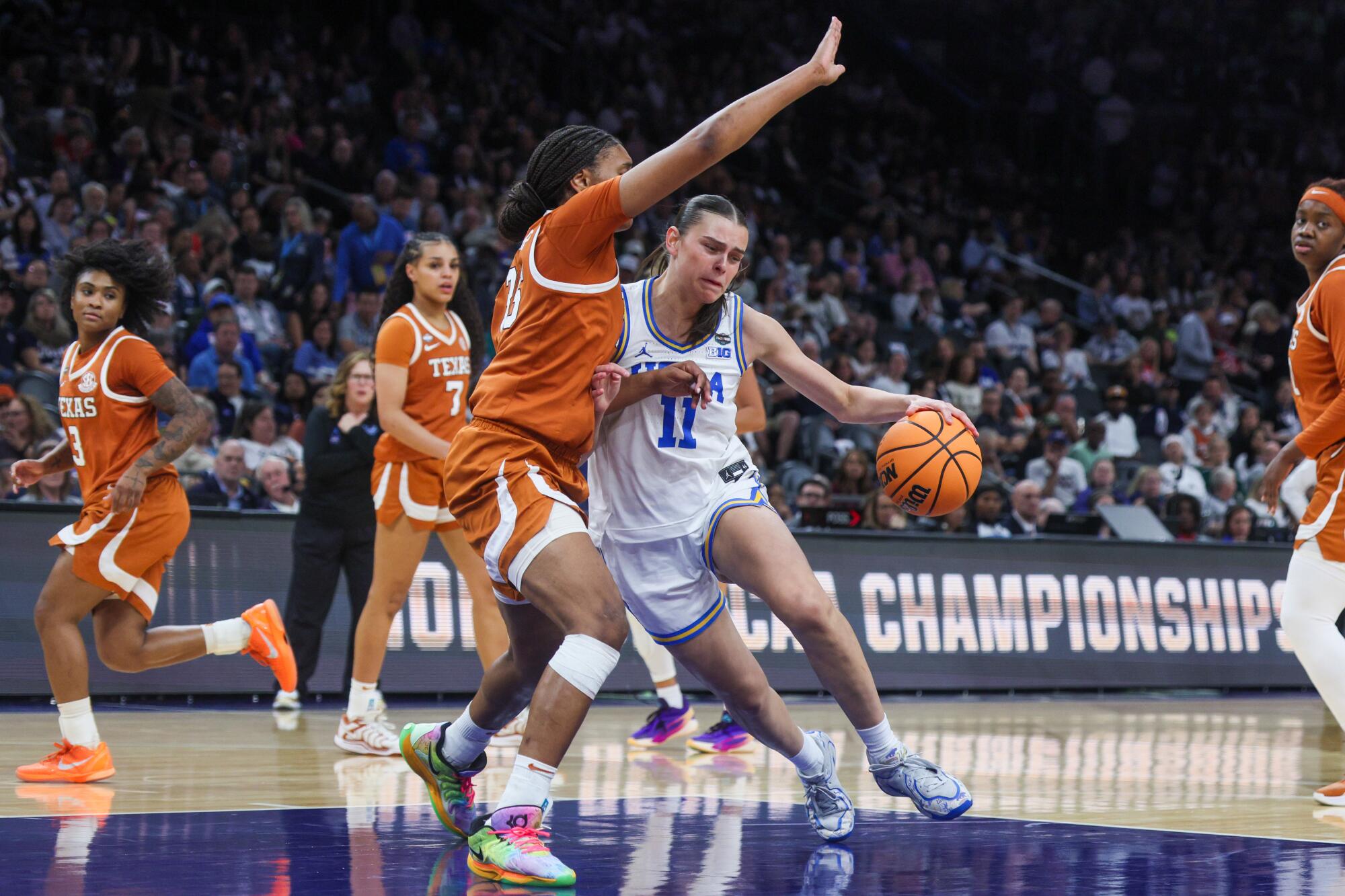 UCLA forward Gabriela Jaquez drives toward the basket under pressure from Texas forward Breya Cunningham.