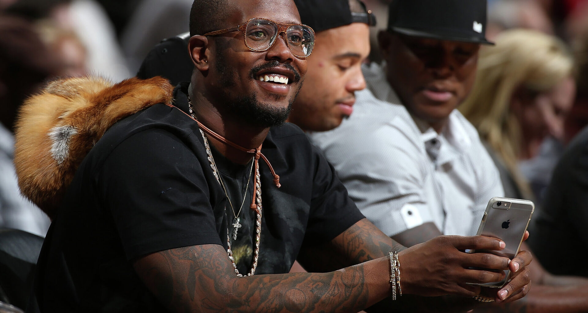 Von Miller of the Denver Broncos uses his iPhone as he watches from courtside as the Houston Rockets face the Denver Nuggets at Pepsi Center on November 13, 2015 in Denver, Colorado. 