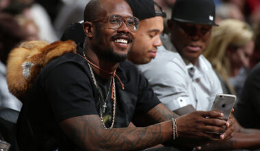 Von Miller of the Denver Broncos uses his iPhone as he watches from courtside as the Houston Rockets face the Denver Nuggets at Pepsi Center on November 13, 2015 in Denver, Colorado. 