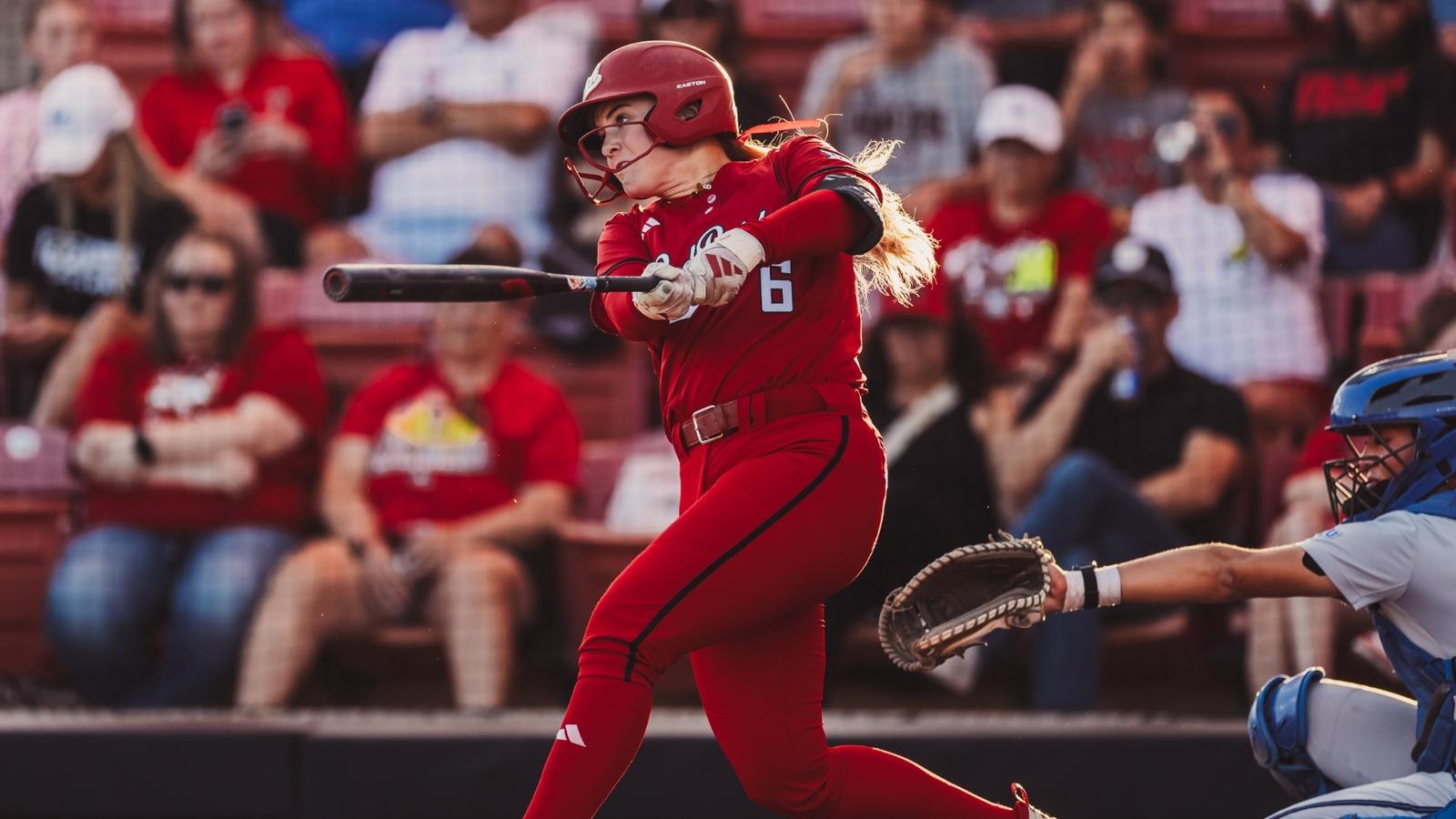 Logan Halleman and Jasmyn Burns hug to celebrate a run being score while wearing white Softball jerseys