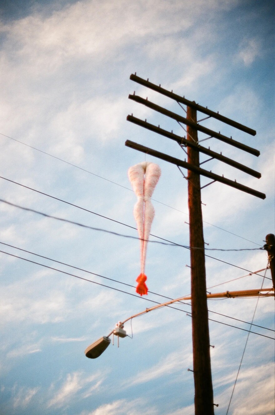 Hairy Legs, made of fabric, polyester fill, and orange yarn, was hung from a telephone pole in 2013.