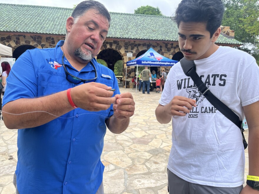 Oscar Castillo shows 14 year-old Joshua Garcia how to tie a hook on the fishing line
