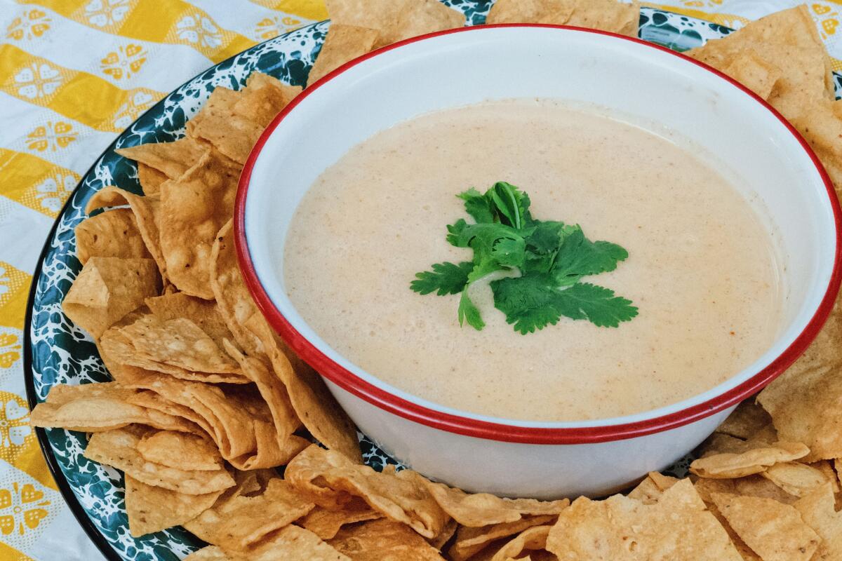 Curry queso, adorned with cilantro, is circled by a ring of tortilla chips