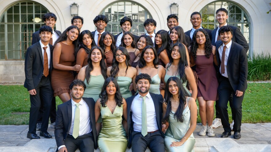 A group of students dressed in suits and dresses pose for a photo. 