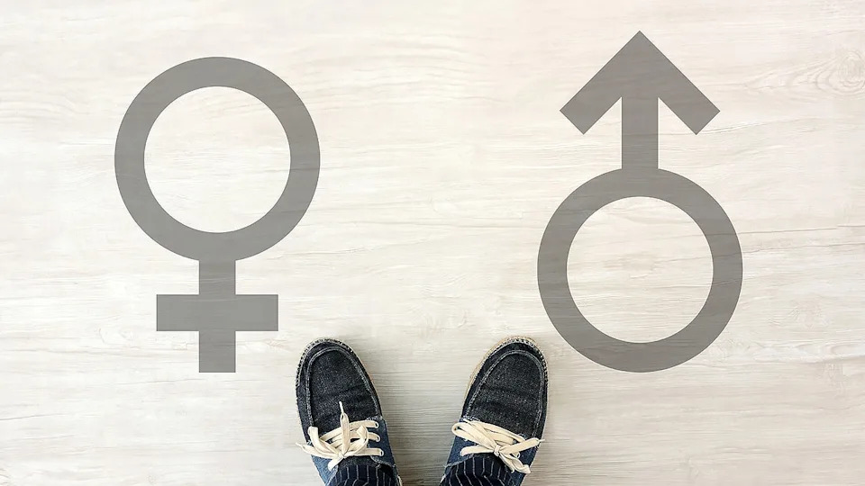 Young person standing between male and female gender symbols on a light background