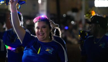 A marcher with Rally Credit Union waves to people at the annual Buc Days Rally Night Parade on Schatzell Street in downtown Corpus Christi on April 26, 2025.