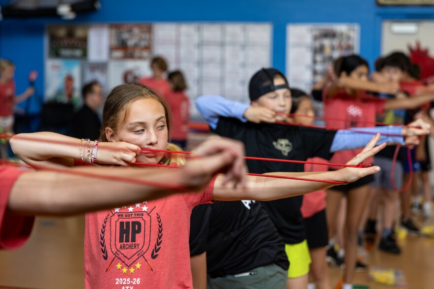 Fifth grader Margot Jacobson does warm-ups by stretching a loop of string at the beginning of after-school archery practice inside the Highland Park Elementary School gym. 
