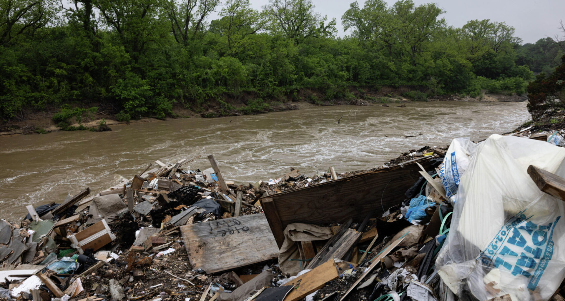 Trash, including building materials, washes into the Trinity River from the illegal dump along the McCommas Bluff.