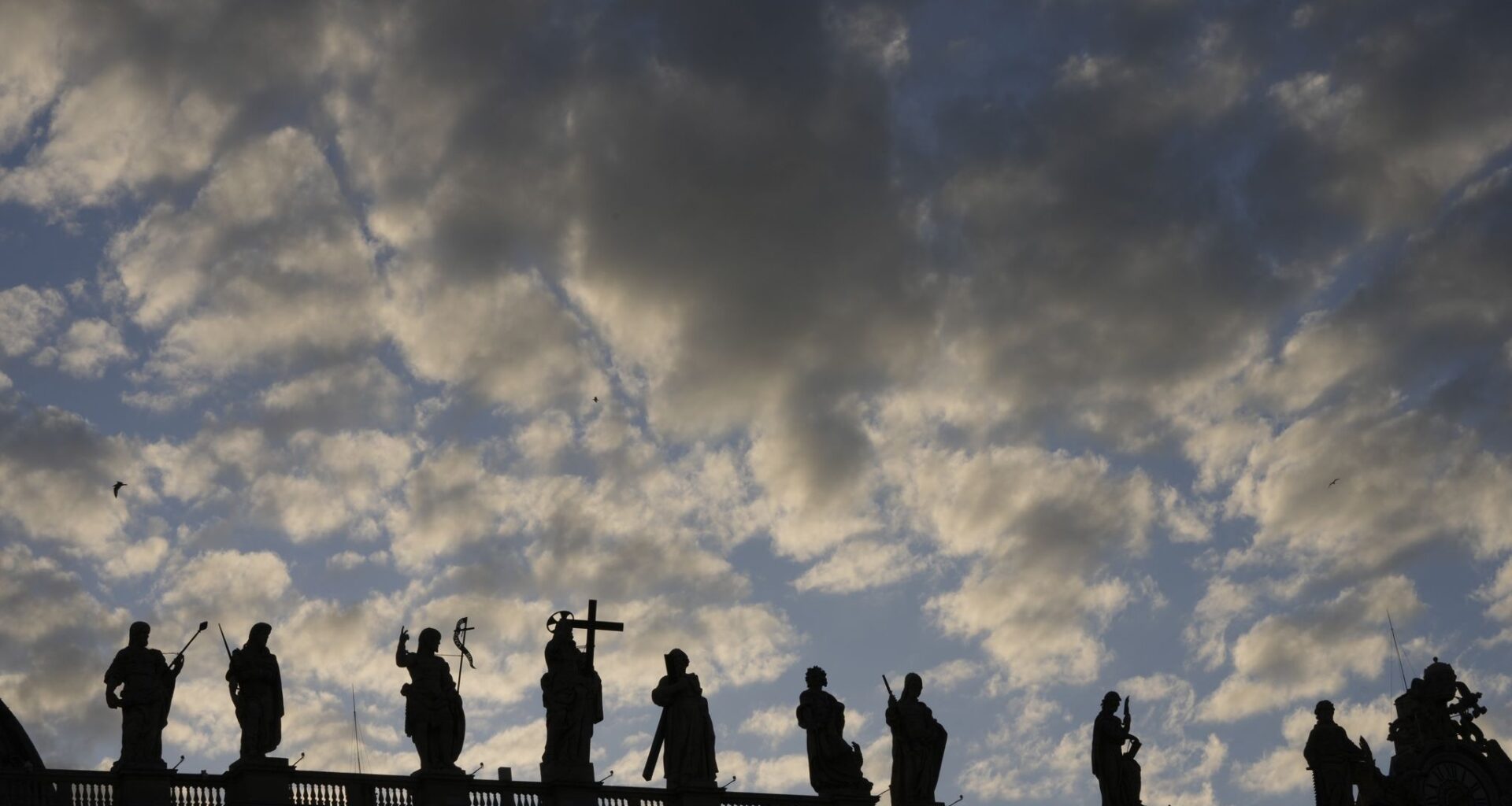 Statues of the Bernini Colonnade are silhouetted against a cloudy sky during the cardinals' conclave to elect a new pope, at the Vatican, Wednesday, May 7, 2025. (AP Photo/Luca Bruno)