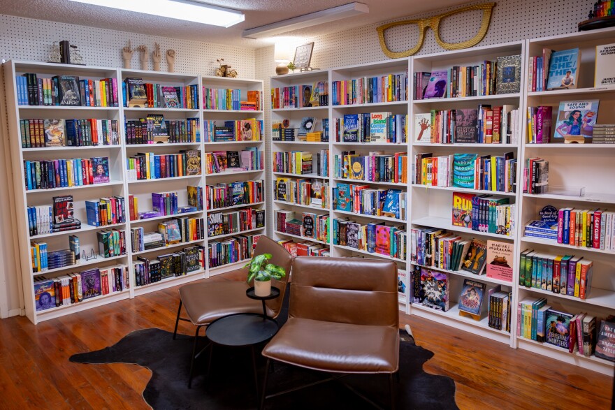 A room full of white bookcases with colorful books filling the shelves.