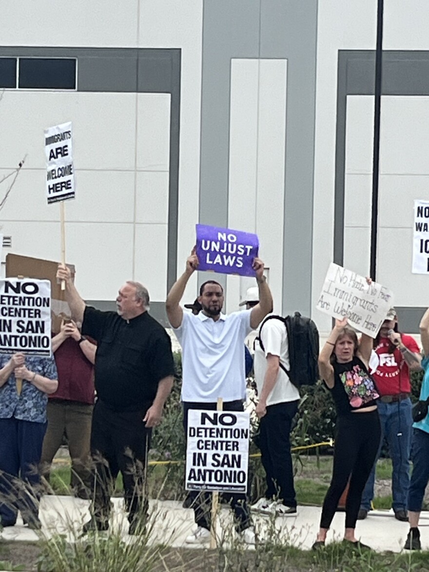Precinct 4 County Commissioner Tommy Calvert (center) holds a protest sign in front the proposed ICE facility on southeast Loop 410 in San Antonio