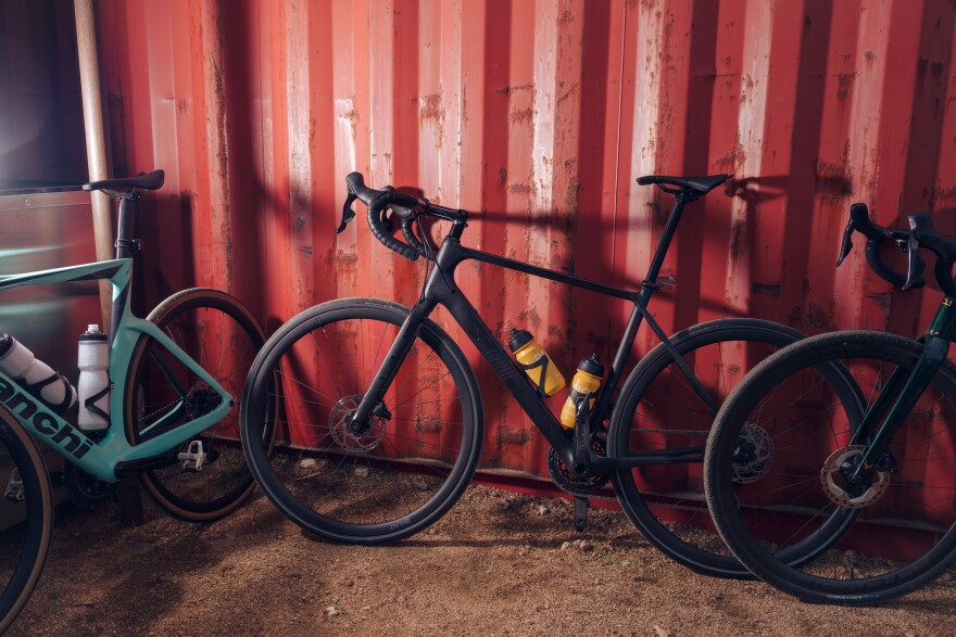 Bikes lean against a red wall.