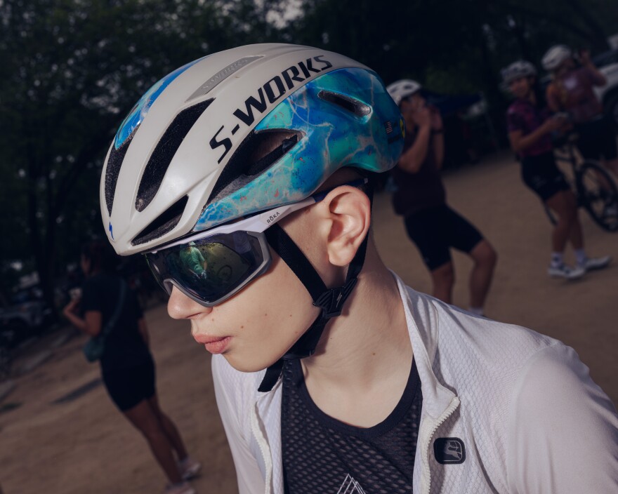 A young boy wears a bicycle helmet and sunglasses.
