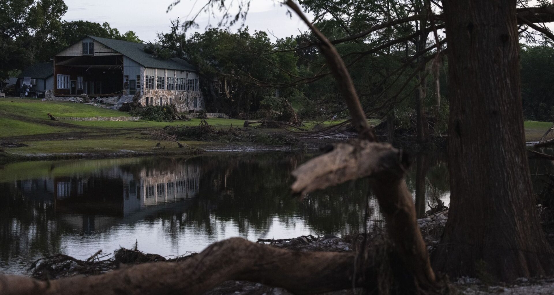 FILE - A building at Camp Mystic is reflected in water after a flash flood swept through the area, on July 7, 2025, in Hunt, Texas. (AP Photo/Eli Hartman, File)