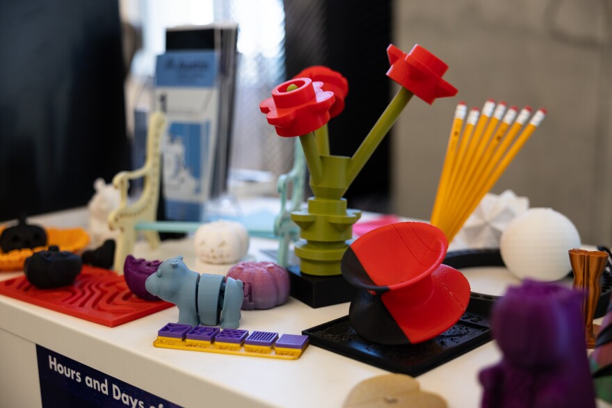 Several 3D printed items sit on a desk, including a flower bouquet, a swivel chair, a pumpkin and more.