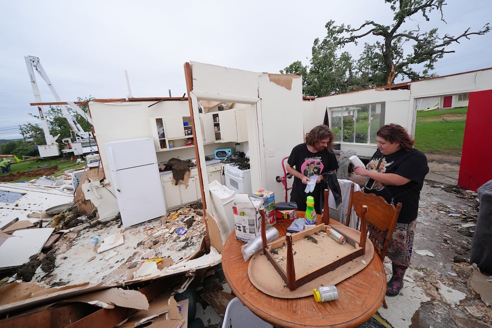 Christopher Hester, left center, talks to friend Brianna Corter, as he salvages belongings...