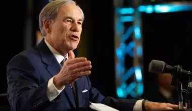 A man gestures with his hand as he speaks at a podium.
