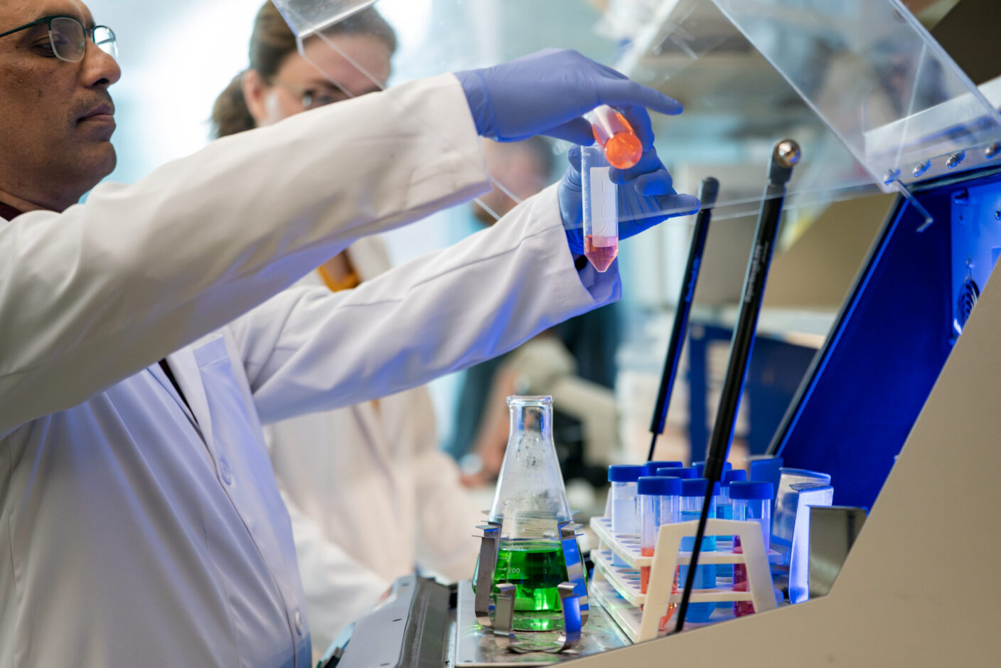 Scenes from the Shetty lab, with two students mixing two solutions into a centrifuge.