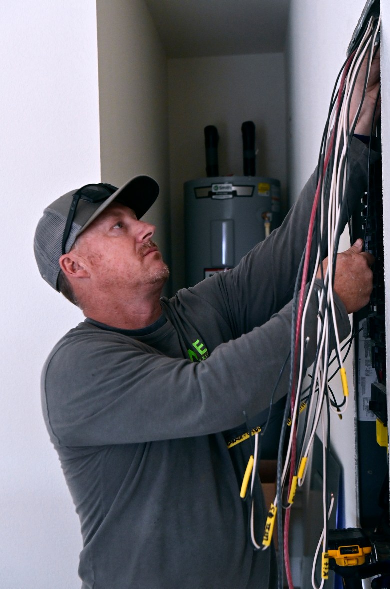 Scotty Wristen, an Abilene electrician, wires a fuse box in a new south Abilene home on April 21, 2026. Wristen has taken to recruiting young people as apprentices in his industry in response to the Abilene DC1 data center depleting the labor pool of local electricians. “I train anybody I can get. We hire them, get them an apprentice card, and start their time on it,” he said.