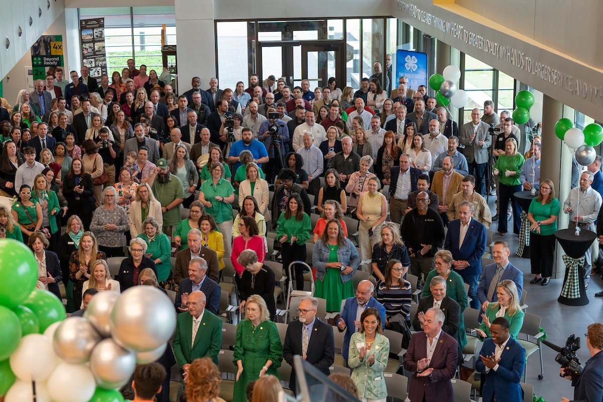 A large group of people stand and sit during a ribbon cutting ceremony for the new Texas 4-H headquarters.
