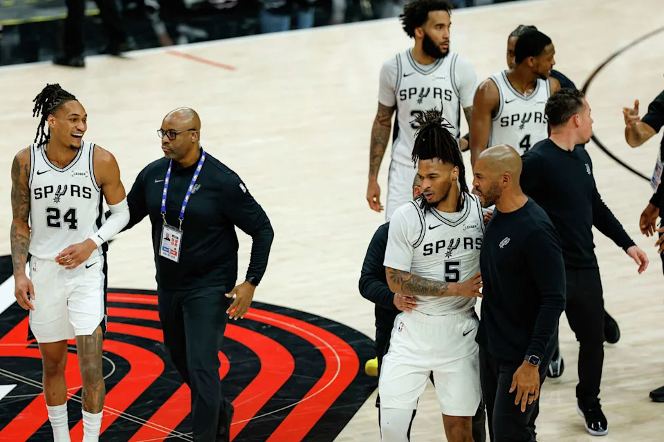 San Antonio Spurs guard <a class="link " href="https://sports.yahoo.com/nba/players/6403/" data-i13n="sec:content-canvas;subsec:anchor_text;elm:context_link" data-ylk="slk:Devin Vassell;sec:content-canvas;subsec:anchor_text;elm:context_link;itc:0" data-yga="{"yLinkElement":"context_link","yModuleName":"content-canvas","yLinkText":"Devin Vassell","ySubModuleName":"anchor_text","yHasCommerce":false}">Devin Vassell</a> (24) smiles as he and San Antonio Spurs guard Stephon Castle (5) are escorted to the bench after a fight broke out between Portland Trail Blazers forward Deni Avdija (8) and Castle during the fourth quarter of Game 4 of a first-round NBA playoff series at Moda Center on Sunday, April 26, 2026. Castle and Avdija both received technical fouls. The Spurs won 114-93, leading the series 3-1.Players (Sam Owens/San Antonio Express-News)