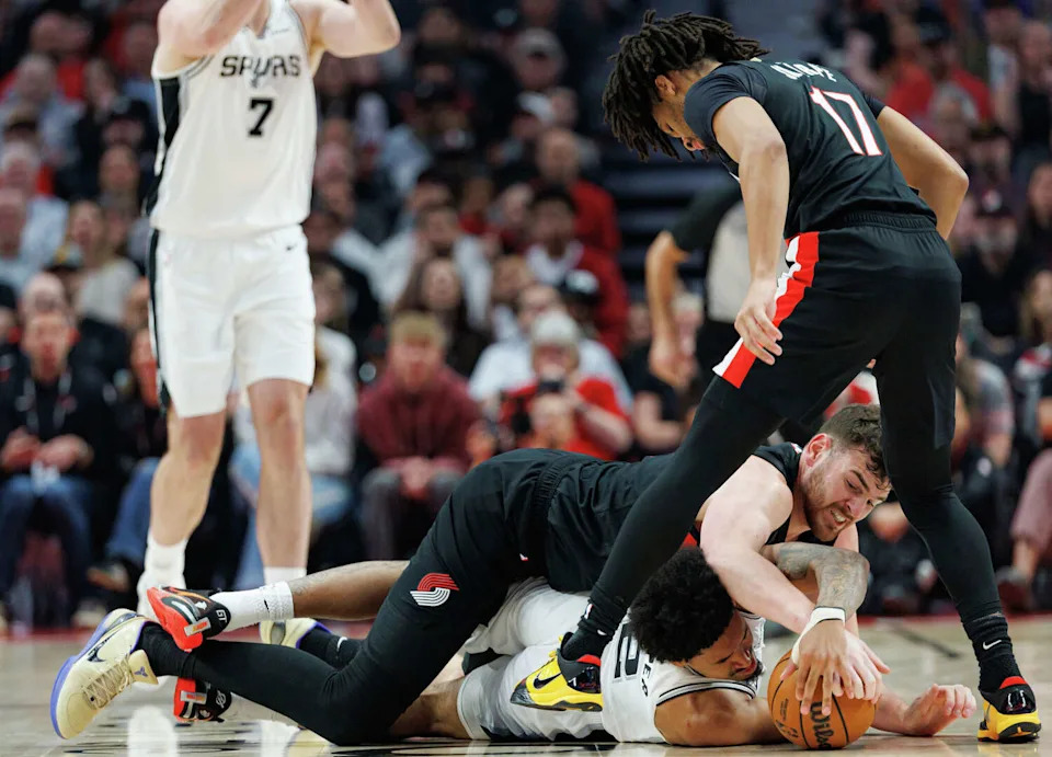 Portland Trail Blazers center <a class="link " href="https://sports.yahoo.com/nba/players/10285/" data-i13n="sec:content-canvas;subsec:anchor_text;elm:context_link" data-ylk="slk:Donovan Clingan;sec:content-canvas;subsec:anchor_text;elm:context_link;itc:0" data-yga="{"yLinkElement":"context_link","yModuleName":"content-canvas","yLinkText":"Donovan Clingan","ySubModuleName":"anchor_text","yHasCommerce":false}">Donovan Clingan</a> (23) and San Antonio Spurs guard Dylan Harper (2) tangle on the ground as they fight for the ball during the first quarter of Game 4 of a first-round NBA playoff series at Moda Center on Sunday, April 26, 2026. (Sam Owens/San Antonio Express-News)