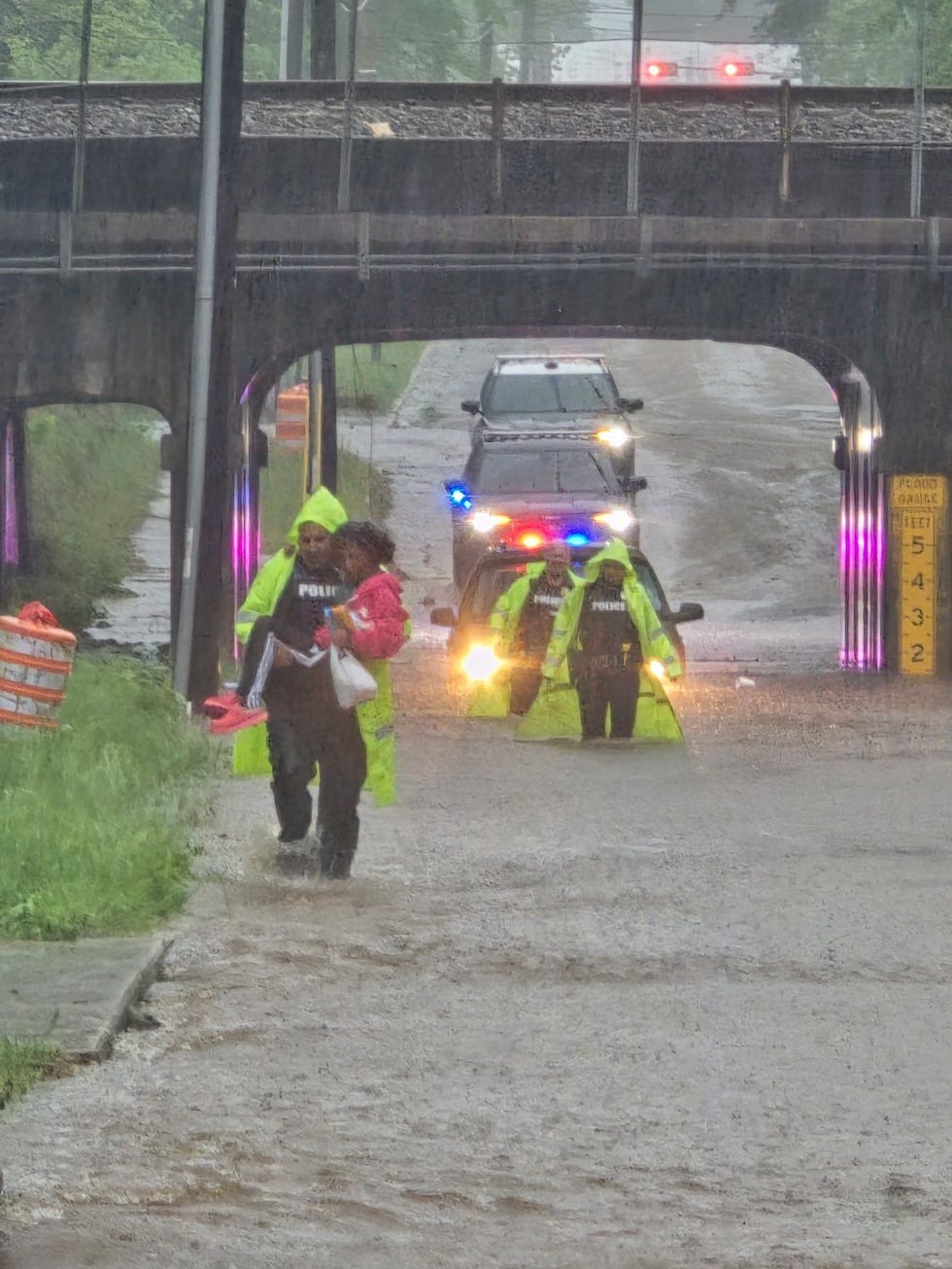 Police carry a woman to safety along a flooded street at the Franklin Street bridge in Marshall.