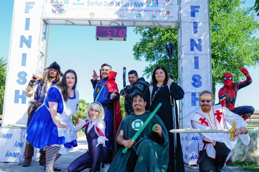Runners at the finish line of a race dressed up in superhero customes.