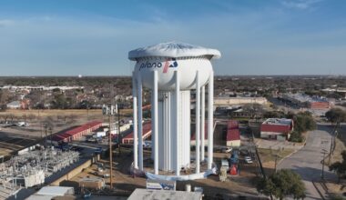 A water tower with a city of Plano logo on the side