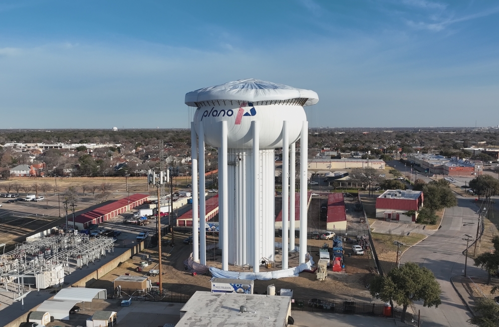 A water tower with a city of Plano logo on the side