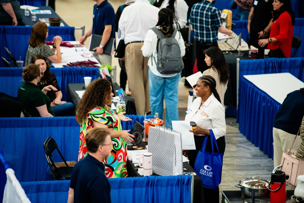 People speaking at a career fair booth