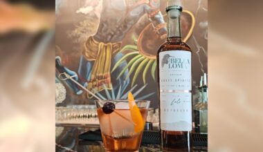 An orange cocktail sits to the left of a bottle of Bella Loma reposado tequila.