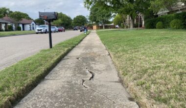 a neighborhood sidewalk with a huge crack in it
