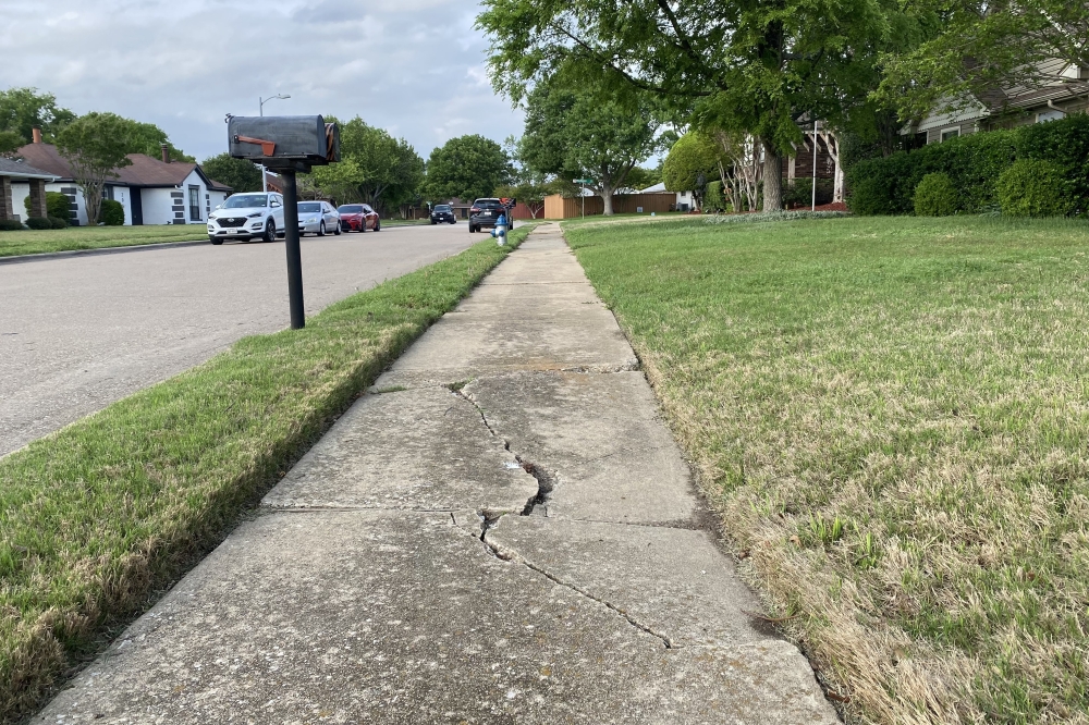 a neighborhood sidewalk with a huge crack in it