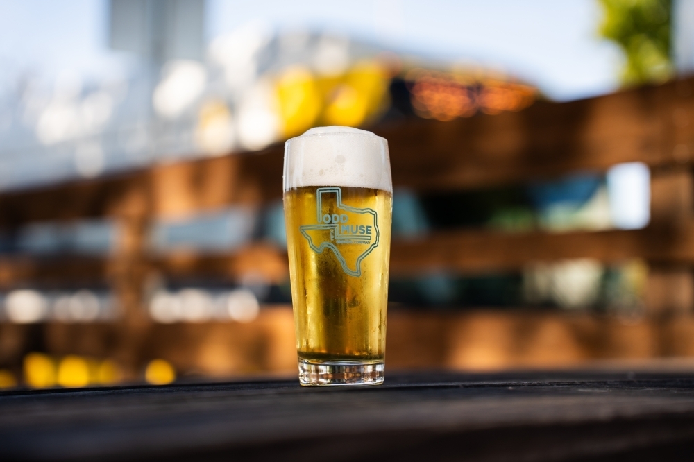 Glass of beer featuring Odd Muse branding.