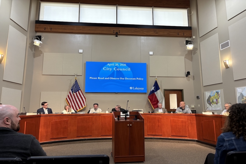 Lakeway City Council chambers with a screen above council members displaying a blue powerpoint.