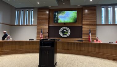 West Lake Hills City Council chambers with a green powerpoint above.