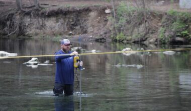 Justin Camp, a Barton Springs-Edwards Aquifer Conservation District hydrogeologist technician, measures flow at Barton Springs. Now in its 45th consecutive month, drought has lowered spring discharge and groundwater levels. (Michael Milliorn/Community Impact)
