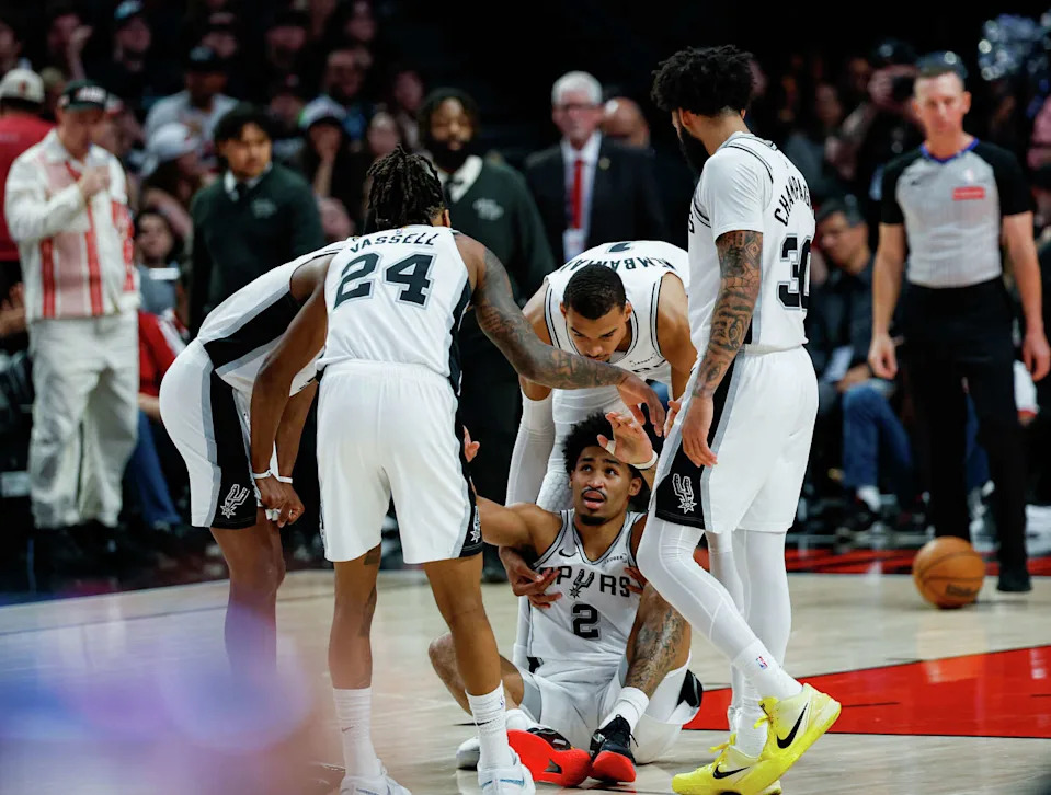 San Antonio Spurs guard <a class="link " href="https://sports.yahoo.com/nba/players/10467/" data-i13n="sec:content-canvas;subsec:anchor_text;elm:context_link" data-ylk="slk:Dylan Harper;sec:content-canvas;subsec:anchor_text;elm:context_link;itc:0" data-yga="{"yLinkElement":"context_link","yModuleName":"content-canvas","yLinkText":"Dylan Harper","ySubModuleName":"anchor_text","yHasCommerce":false}">Dylan Harper</a> (2) is helped up by his teammates after falling while playing defense against the Portland Trail Blazers during the second quarter of Game 4 of a first-round NBA playoff series at Moda Center on Sunday, April 26, 2026. (Sam Owens/San Antonio Express-News)