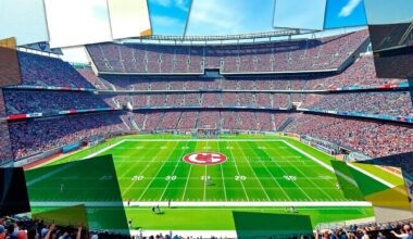 A fragmented, cubist-style painting depicting a football game at AT&T Stadium, with the players, field, and stadium architecture broken down into sharp, overlapping geometric shapes and planes of vibrant color.