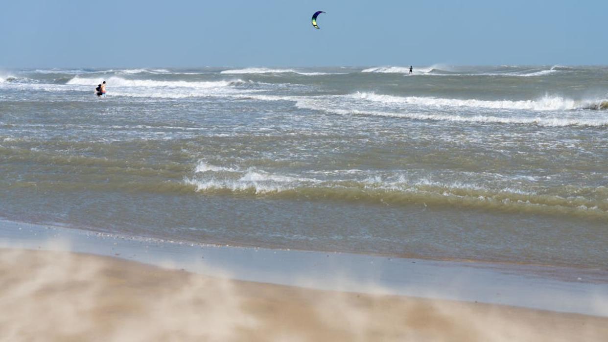 <div>Strong winds blow sand across the beach as a kite surfer rides and a couple plays in the heavy surf. South Padre Island, Texas. (Photo by: Jon G. Fuller/VW Pics/Universal Images Group via Getty Images)</div>
