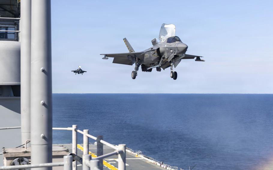 The first F-35 hovers over the flight deck, the second jet closes in.