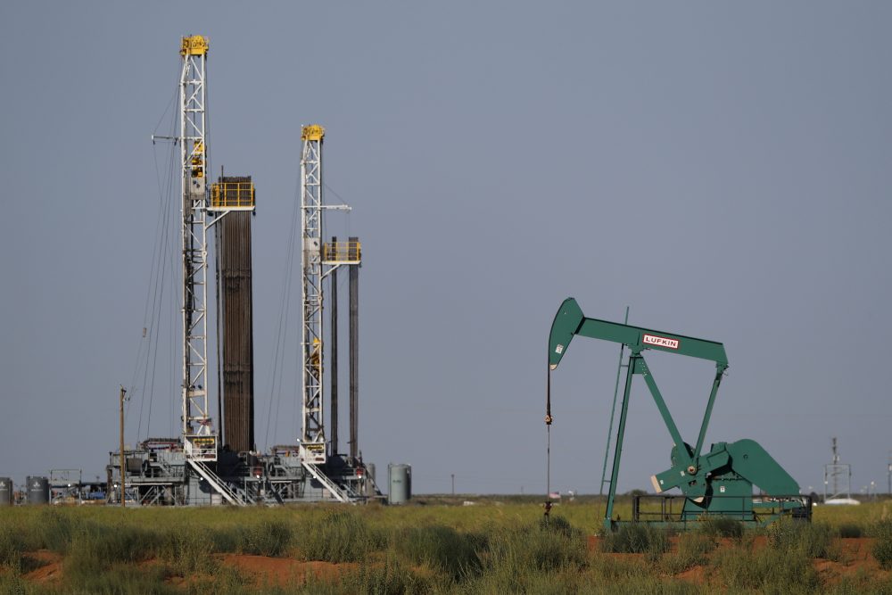 Oil rigs and a pump jack are shown in a rural area, Wednesday, July 29, 2020, in Midland, Texas. 