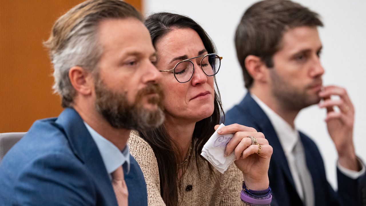 Holding a handkerchief embroidered with her daughter's name, CiCi Steward, who lost her 8-year-old daughter Cile Steward in the July 4 flood, listens to testimony alongside her husband, Will Steward, during a hearing on a suit against Camp Mystic in the 459th State District Court in Austin, Wednesday, April 15, 2026. (Mikala Compton/Austin American-Statesman via AP)