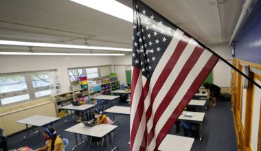 An American flag hangs in a classroom as students work on laptops in Newlon Elementary School, Aug. 25, 2020, in Denver. (AP Photo/David Zalubowski)