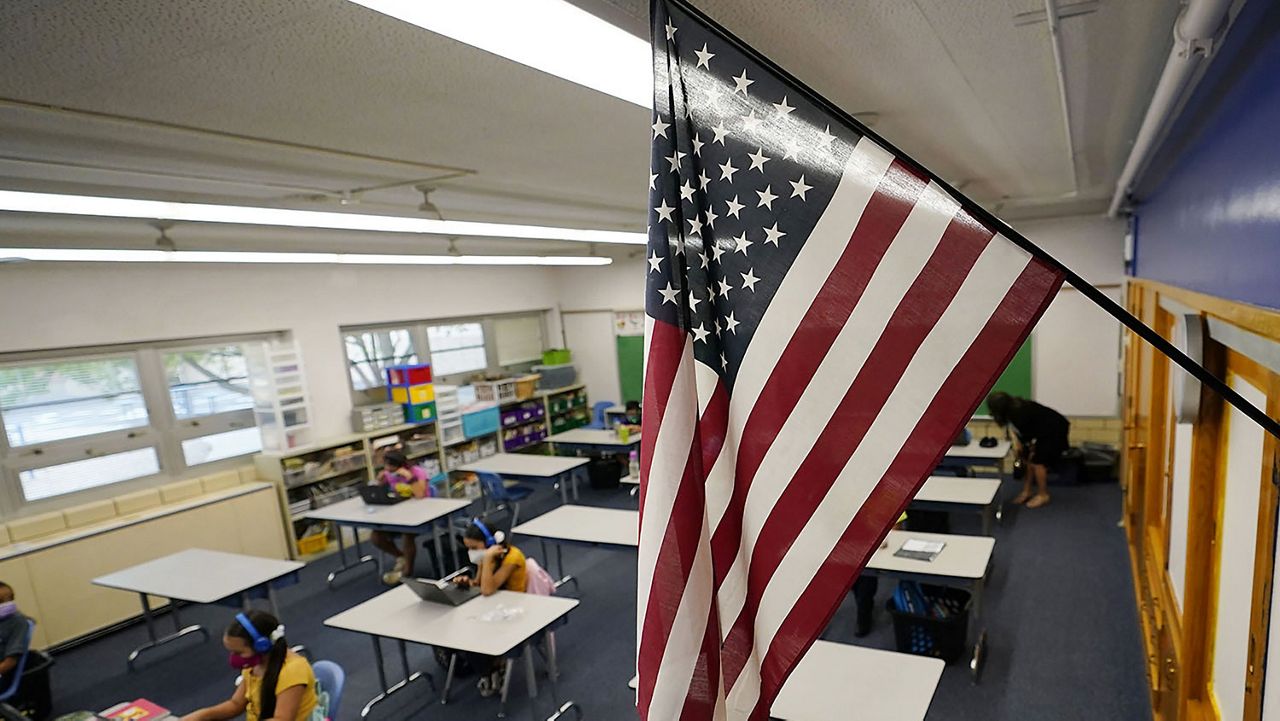 An American flag hangs in a classroom as students work on laptops in Newlon Elementary School, Aug. 25, 2020, in Denver. (AP Photo/David Zalubowski)